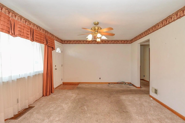 empty room with visible vents, baseboards, light colored carpet, and ceiling fan