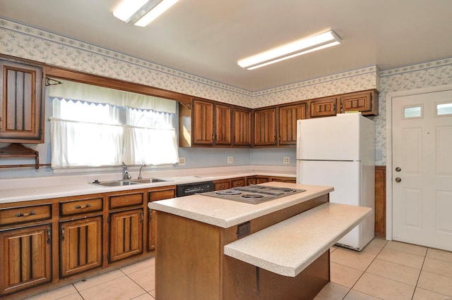 kitchen featuring light tile patterned floors, wallpapered walls, freestanding refrigerator, and a sink