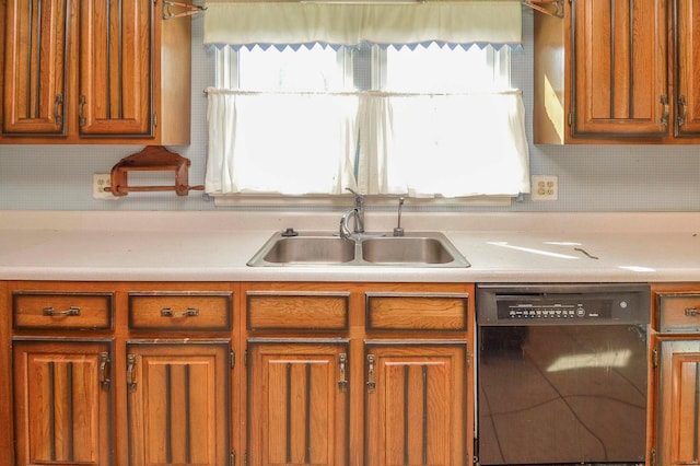 kitchen with brown cabinets, light countertops, black dishwasher, and a sink