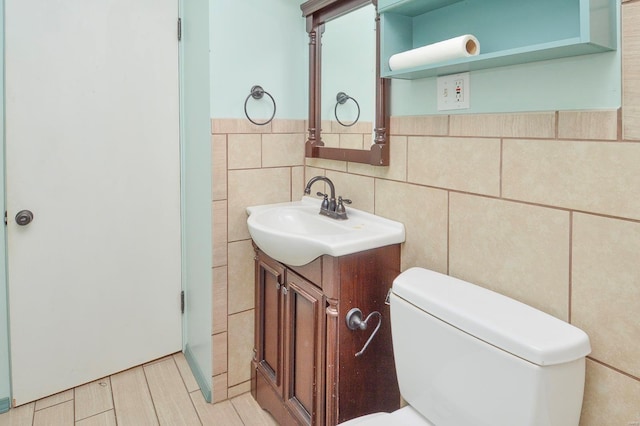 half bath with vanity, tile walls, and toilet