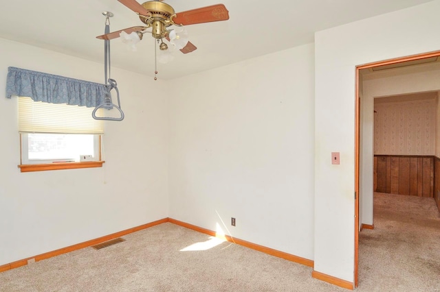 carpeted empty room with visible vents, baseboards, and a ceiling fan