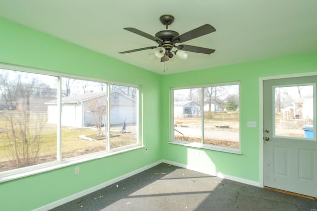 unfurnished sunroom featuring a wealth of natural light and a ceiling fan