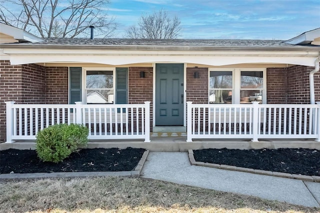 doorway to property with brick siding and a porch