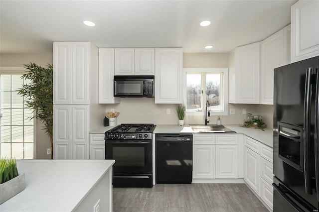 kitchen with black appliances, white cabinets, light countertops, and a sink