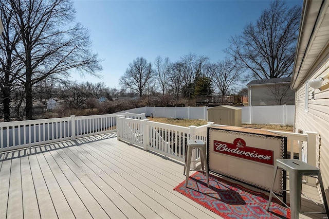 wooden deck with an outbuilding, a fenced backyard, and a shed