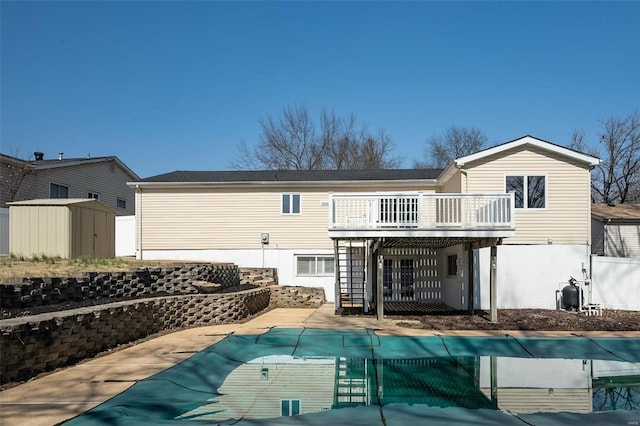 rear view of property with an outbuilding, a covered pool, a storage unit, a deck, and a patio area