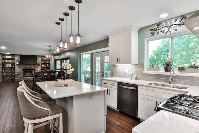 kitchen with backsplash, a brick fireplace, french doors, stainless steel dishwasher, and a sink