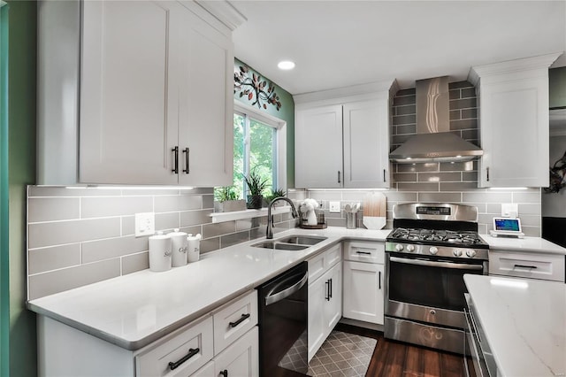 kitchen with stainless steel range with gas cooktop, wall chimney range hood, dishwasher, white cabinets, and a sink