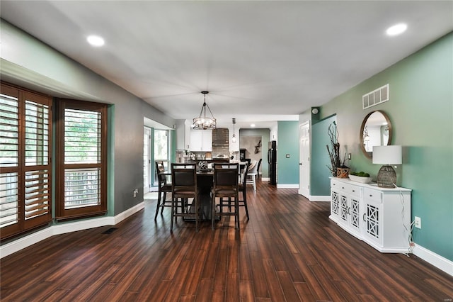 dining space with visible vents, baseboards, a notable chandelier, and dark wood finished floors