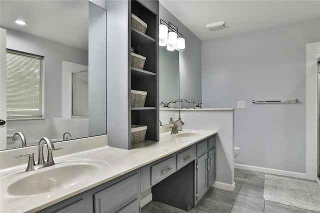 bathroom featuring a sink, baseboards, toilet, and double vanity