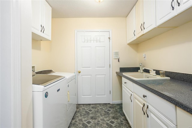 laundry room with baseboards, cabinet space, a sink, a textured ceiling, and washer and clothes dryer