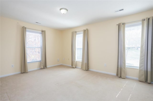 unfurnished room with plenty of natural light, visible vents, and carpet floors