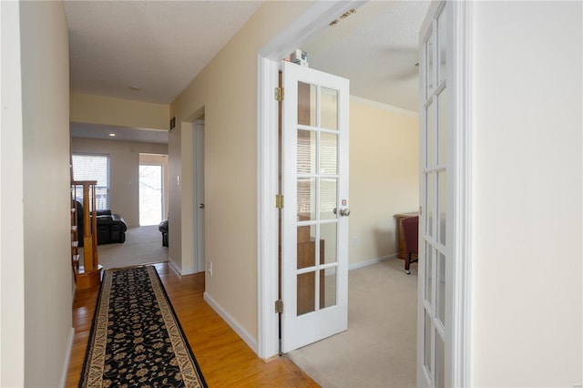 hall featuring french doors, light wood-style floors, and baseboards