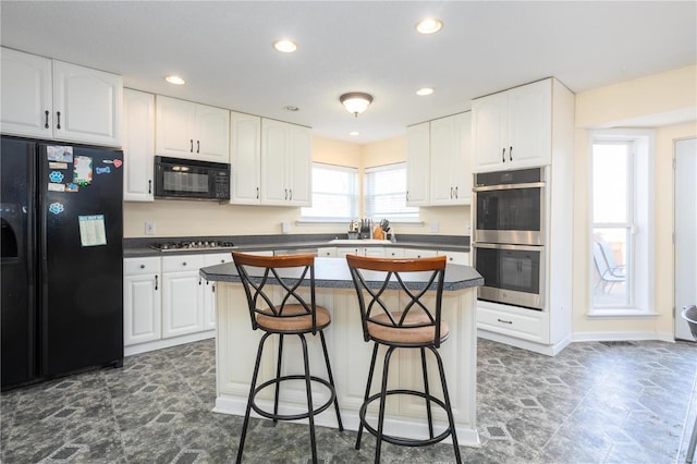 kitchen featuring a breakfast bar, black appliances, dark countertops, and a kitchen island