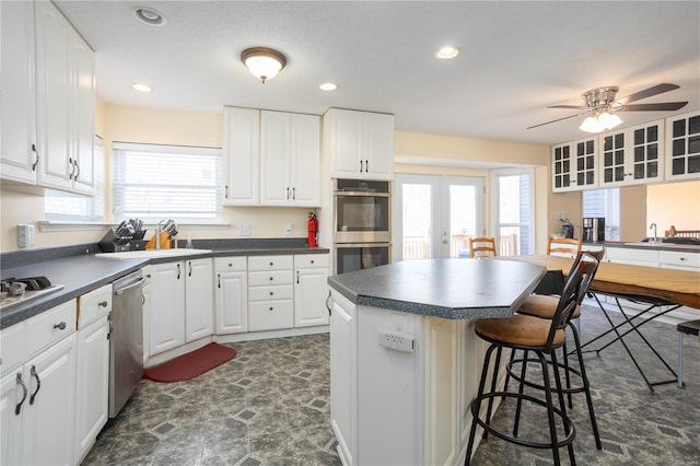 kitchen featuring dark countertops, white cabinetry, a kitchen breakfast bar, and stainless steel appliances