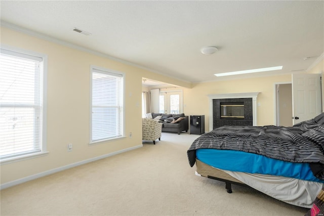 bedroom with visible vents, baseboards, light colored carpet, ornamental molding, and a fireplace