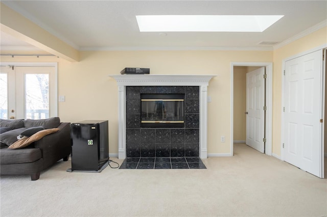 living area with baseboards, ornamental molding, carpet floors, a tile fireplace, and a skylight