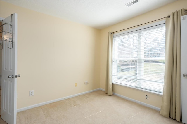 empty room with baseboards, visible vents, and light carpet