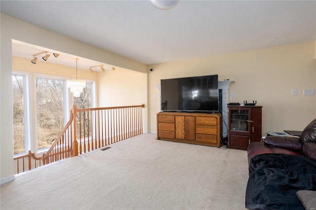 living room with visible vents, light carpet, a notable chandelier, track lighting, and a textured ceiling