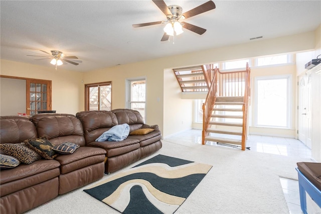 living room with a wealth of natural light, visible vents, a ceiling fan, and stairway