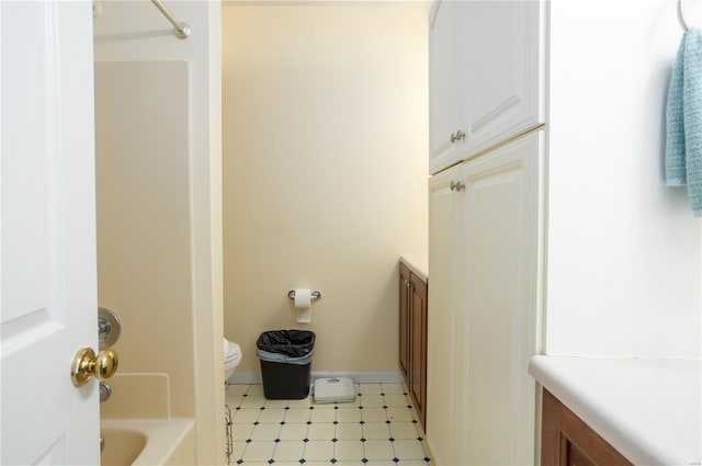 bathroom featuring vanity, baseboards, bathtub / shower combination, tile patterned floors, and toilet