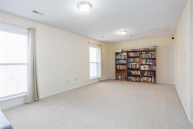 unfurnished room with visible vents, light colored carpet, attic access, and a healthy amount of sunlight