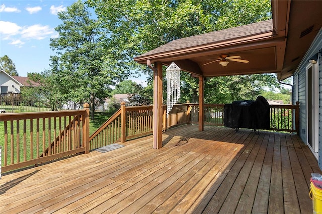 wooden terrace with area for grilling, fence, a lawn, and ceiling fan