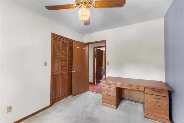 unfurnished office with baseboards, light carpet, and a ceiling fan