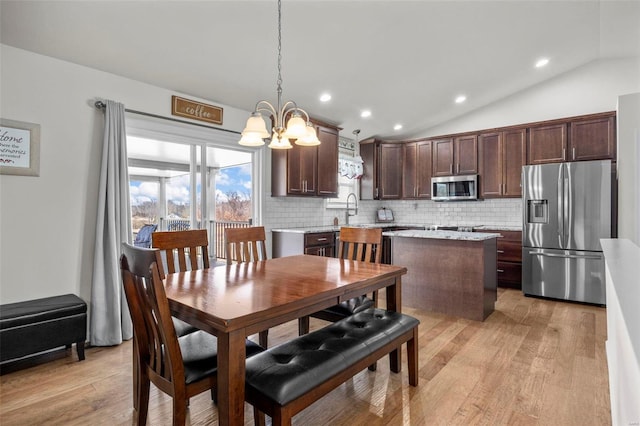 dining space featuring vaulted ceiling, recessed lighting, light wood-type flooring, and a chandelier