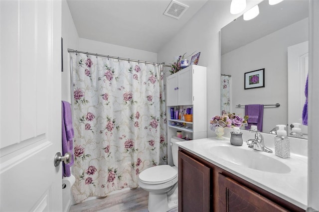 bathroom featuring vanity, a shower with shower curtain, wood finished floors, visible vents, and toilet