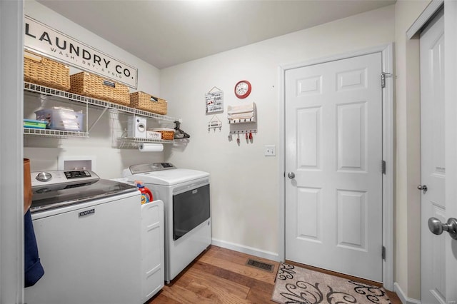 washroom featuring light wood-type flooring, visible vents, separate washer and dryer, baseboards, and laundry area