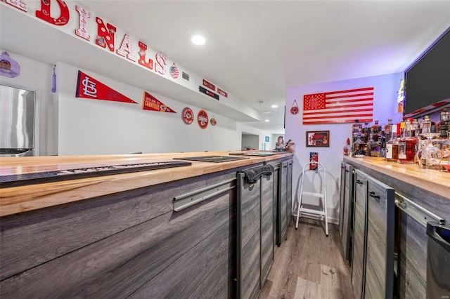 bar featuring recessed lighting, a bar, and light wood-style floors