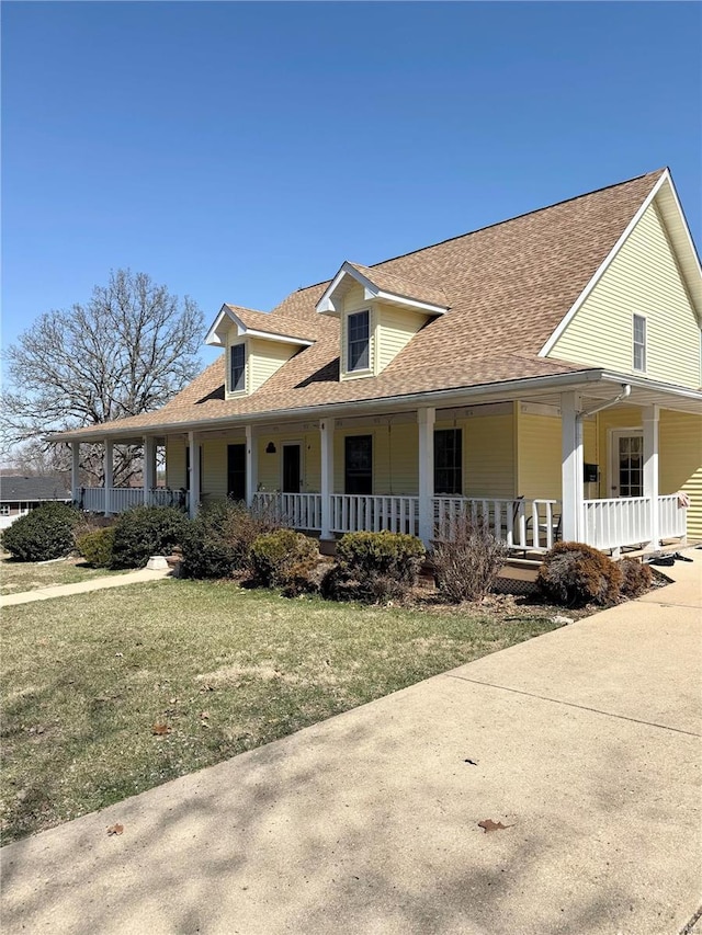 farmhouse inspired home with covered porch, a front yard, and roof with shingles