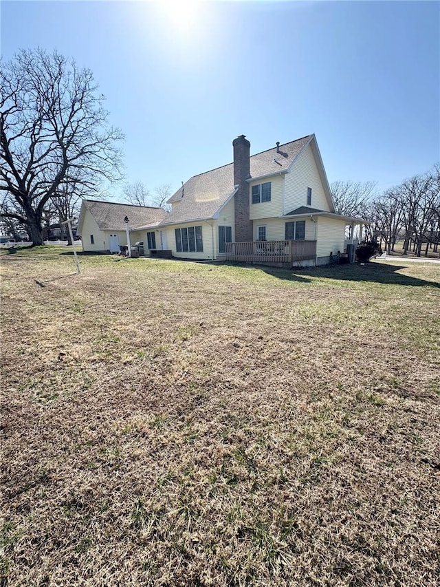 back of house featuring a lawn and a chimney