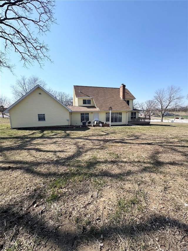 back of house featuring a chimney and a yard