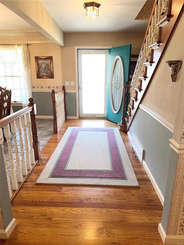 foyer entrance with wood finished floors, visible vents, and baseboards