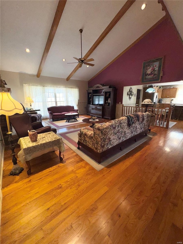 living room featuring beamed ceiling, high vaulted ceiling, wood finished floors, and a ceiling fan