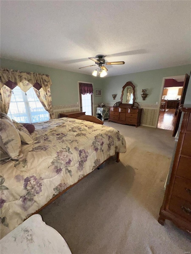 carpeted bedroom with multiple windows, a textured ceiling, and a ceiling fan