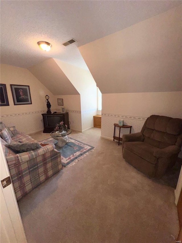 living area with lofted ceiling, visible vents, carpet floors, and a textured ceiling