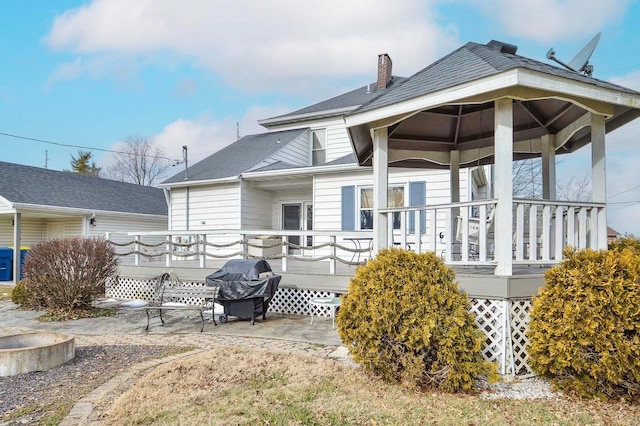 back of property featuring a chimney and a shingled roof