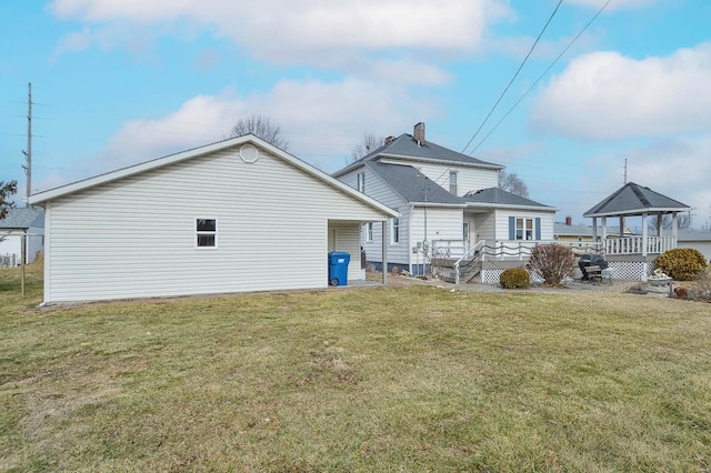 rear view of house with a gazebo, a deck, a chimney, and a yard