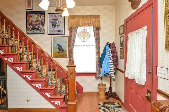 foyer entrance featuring stairway, plenty of natural light, wallpapered walls, and wood finished floors