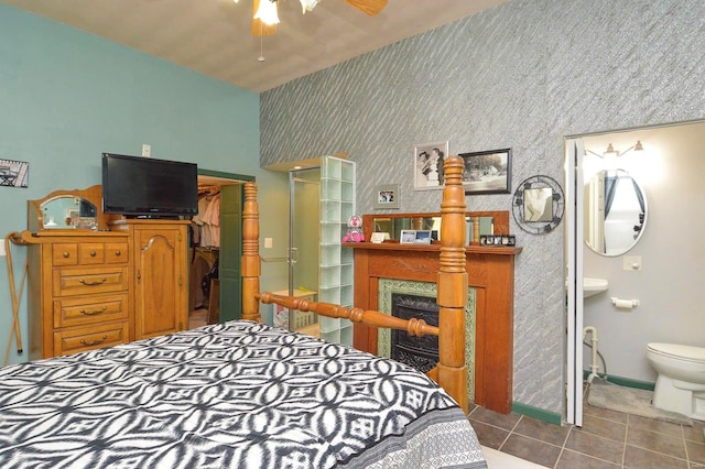 tiled bedroom featuring a spacious closet, connected bathroom, wallpapered walls, baseboards, and a fireplace