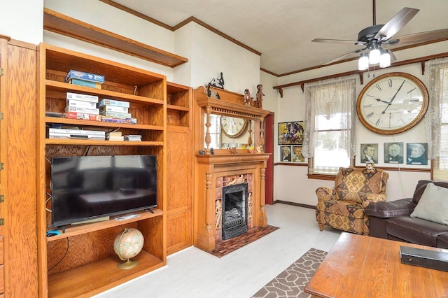 living area with ceiling fan, a fireplace with flush hearth, wood finished floors, and ornamental molding