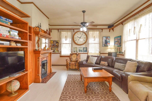 living room featuring a tiled fireplace, wood finished floors, ceiling fan, and ornamental molding