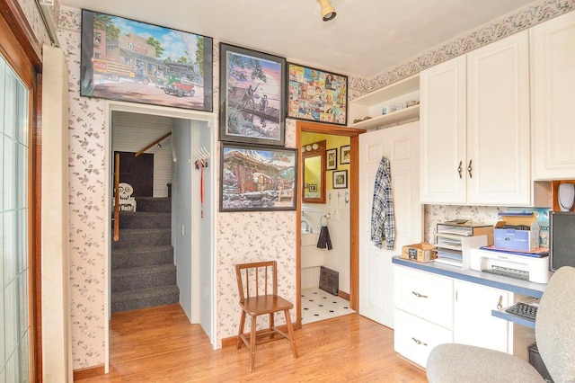 kitchen with white cabinets, wallpapered walls, and light wood-type flooring