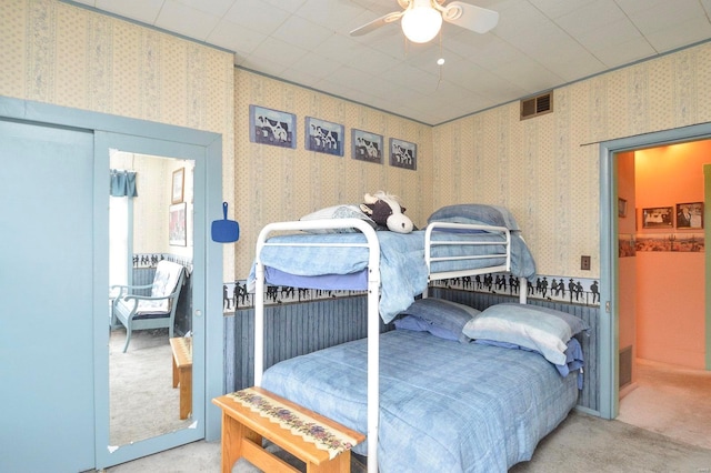 carpeted bedroom featuring wallpapered walls, visible vents, and ceiling fan