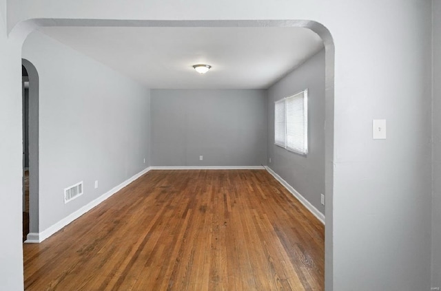 spare room featuring visible vents, baseboards, and wood finished floors