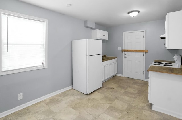 kitchen featuring white appliances, white cabinets, and baseboards