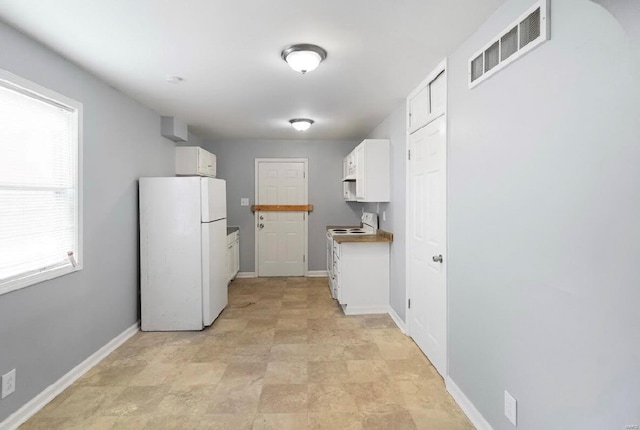 kitchen featuring visible vents, white appliances, baseboards, and white cabinetry